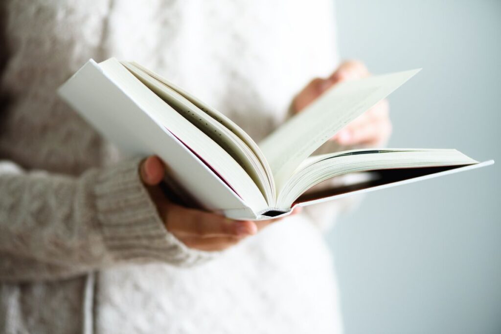 Young girl in white T shirt reading opened book. Copy space. lifestyle and school concept