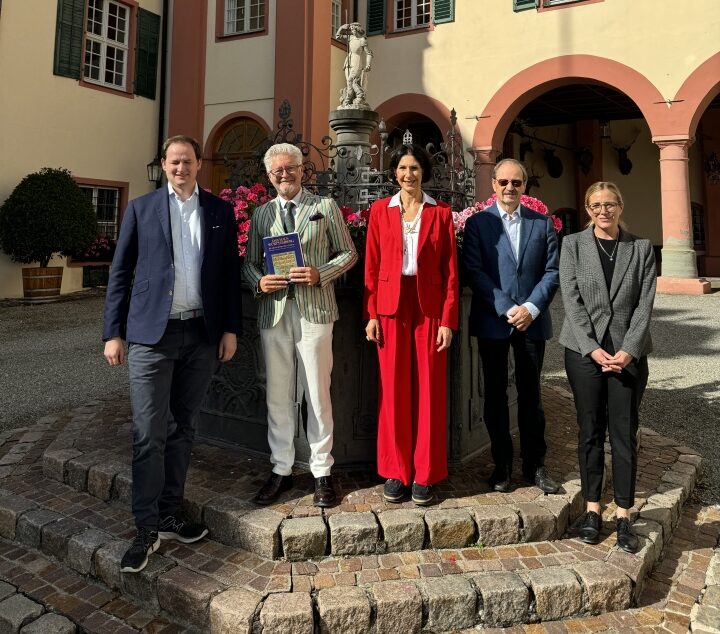 Fünf Personen stehen nebeneinander vor einem Brunnen
